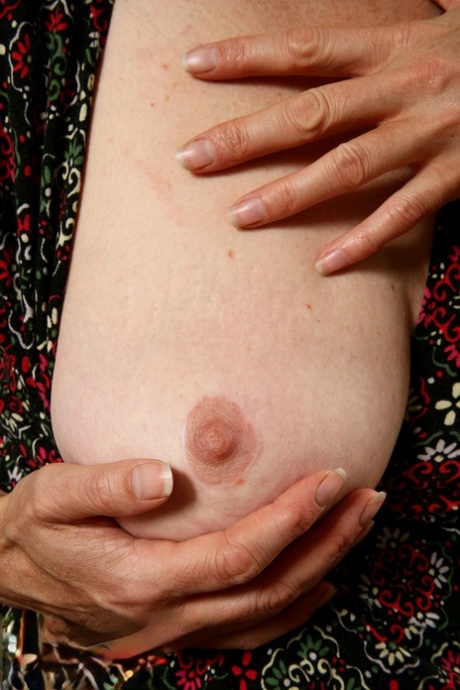 Older woman cups a boob before showcasing her hairy bush on her sofa